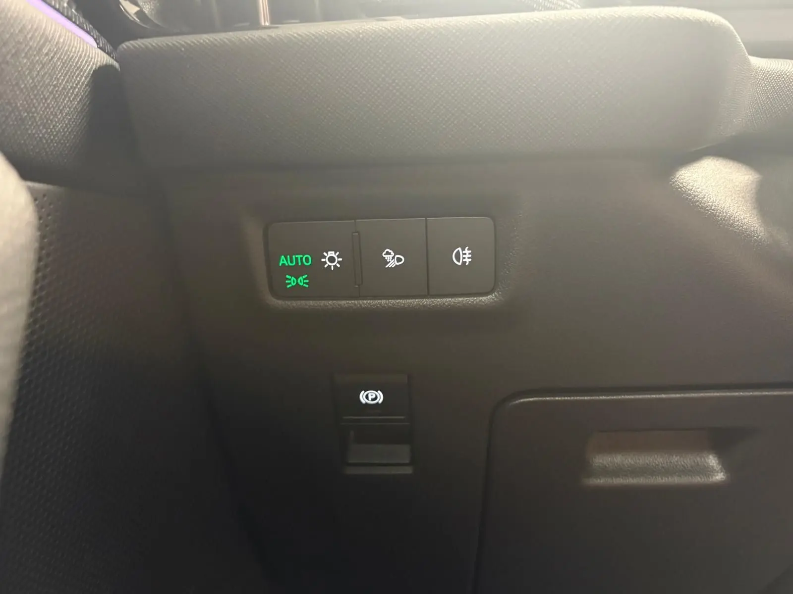 Détail intérieur du tableau de bord côté gauche du Skoda Kodiaq gris graphite, avec commandes d’éclairage et frein à main électrique.
