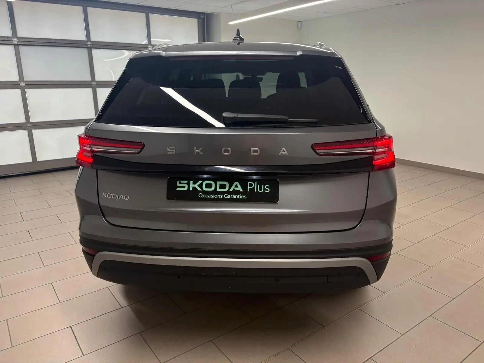 Vue arrière d’un Skoda Kodiaq gris graphite 2025 avec feux LED allumés dans un showroom intérieur.