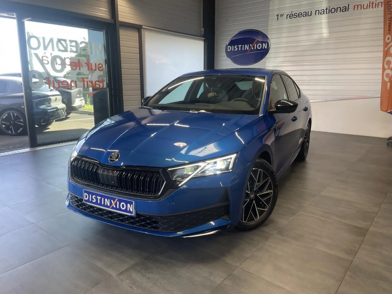 Skoda Octavia 2025 bleu foncé vue 3/4 avant en intérieur avec jantes alliage noires et calandre marquée.