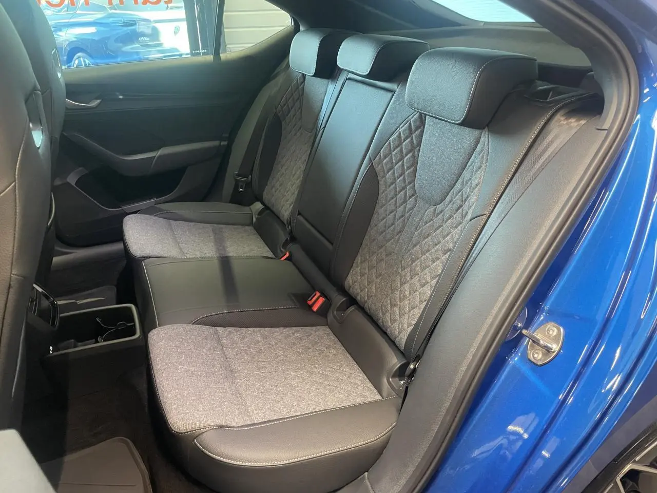 Vue intérieure côté droit sur la banquette arrière bi-matière grise et noire d’une Skoda Octavia bleu foncé 2025 Sportline.