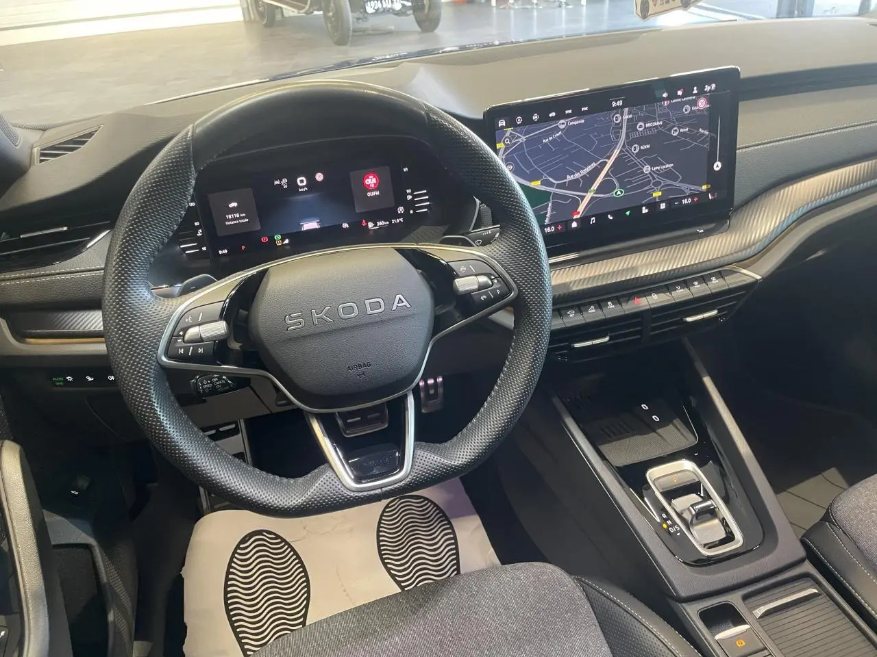 Intérieur Skoda Octavia 2025 vu de face, volant sport cuir, tableau de bord numérique et écran tactile GPS.