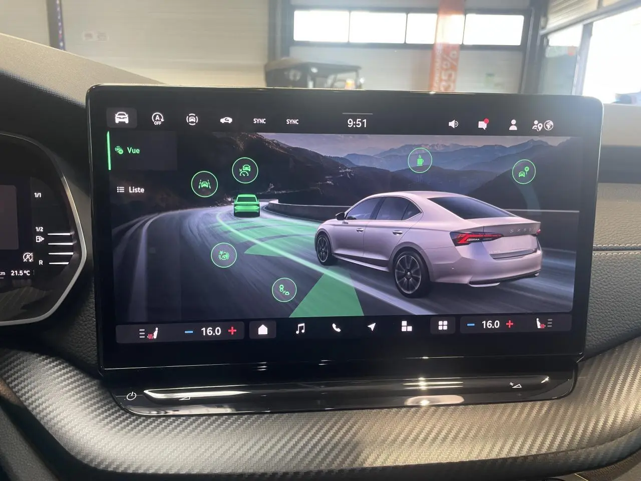 Écran tactile intérieur montrant une Skoda Octavia 2025 gris clair en vue 3/4 arrière sur route sinueuse.