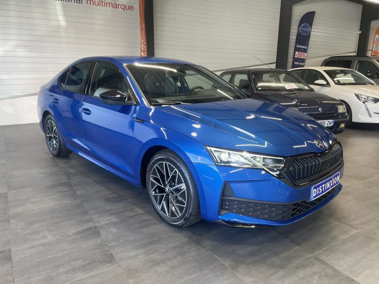 Vue 3/4 avant d'une Skoda Octavia 2025 bleu foncé avec jantes alliage noires et calandre noire sportive.