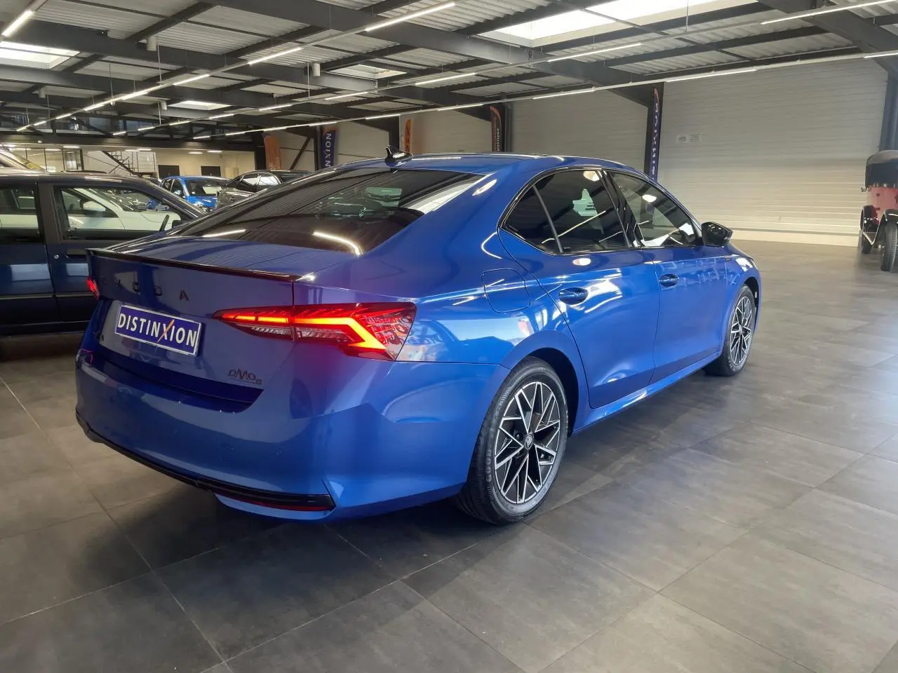 Vue 3/4 arrière droite d'une Skoda Octavia Sportline bleu foncé avec jantes alliage noires et feux arrière LED défilants.