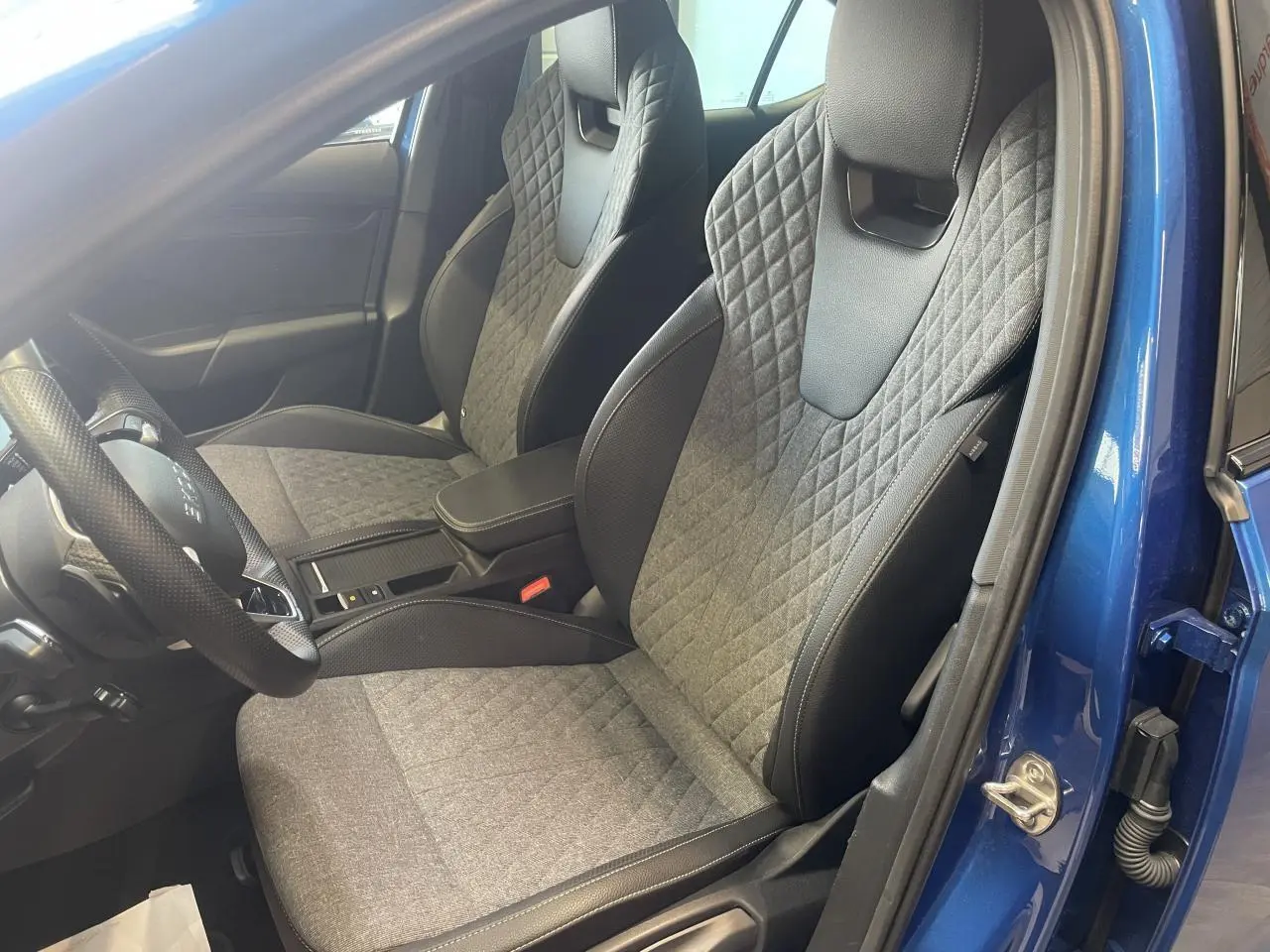 Vue intérieure côté conducteur de la Skoda Octavia 2025 bleu foncé, sièges sport en tissu et cuir avec surpiqûres.