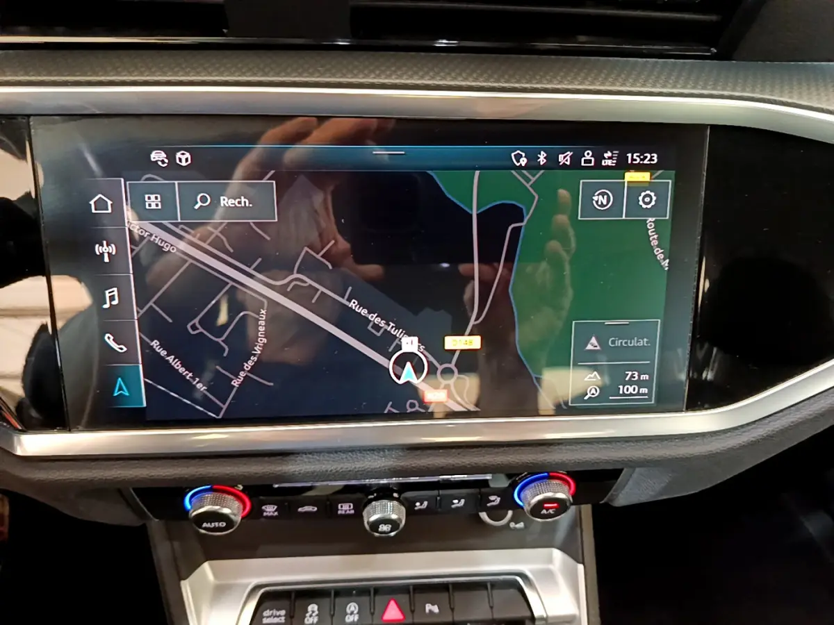 Vue rapprochée de l’écran tactile central du tableau de bord de l’Audi Q3 noir, affichant la navigation GPS.