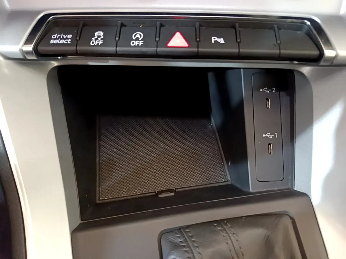 Vue rapprochée de la console centrale noire de l'Audi Q3 35 TDI 2021 avec boutons de contrôle et ports USB visibles.