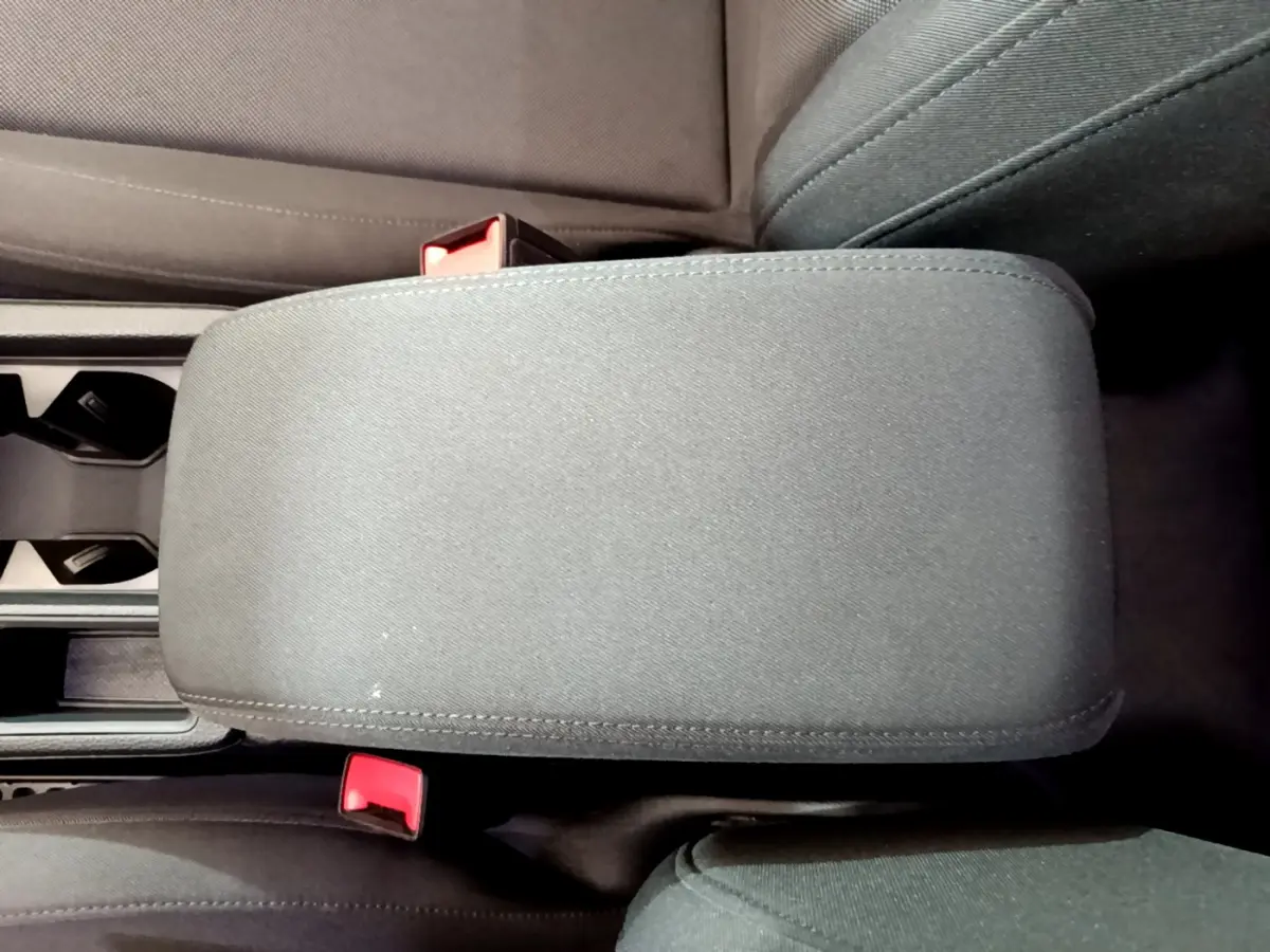 Vue rapprochée de l'accoudoir central noir et des sièges avant en tissu dans l'Audi Q3 35 TDI 2021.