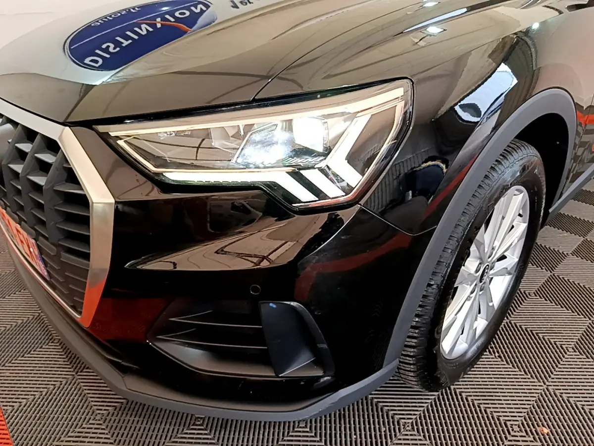 Gros plan sur l'avant droit noir d'un Audi Q3 35 TDI 150 S tronic avec phare LED et jante argentée.