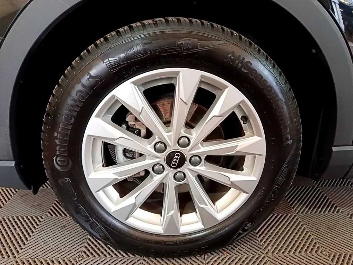 Gros plan sur la roue avant gauche d’un Audi Q3 noir, mettant en valeur la jante alu à design étoilé.