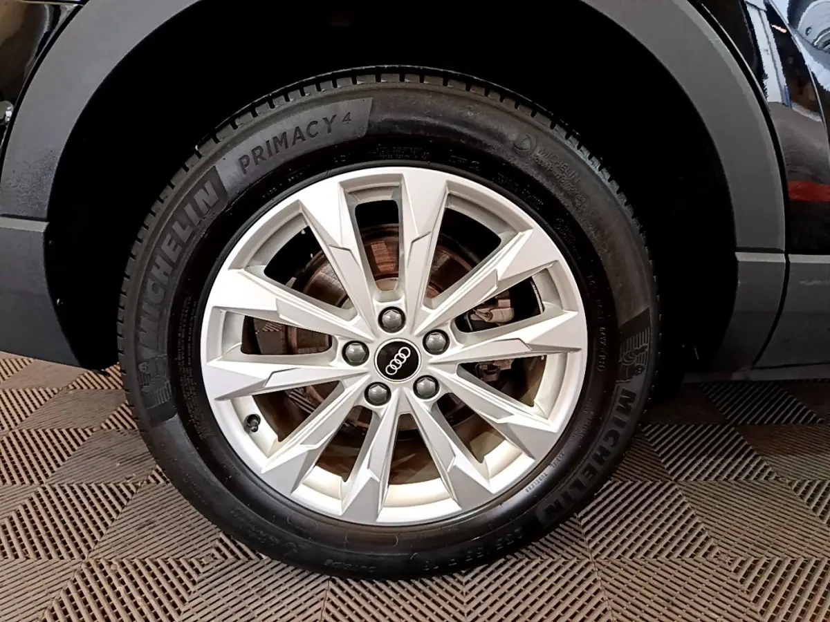 Gros plan sur la roue avant droite d’un Audi Q3 noir, mettant en valeur la jante alliage argentée et le pneu Michelin.