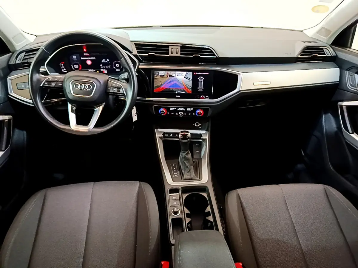 Vue intérieure avant de l'Audi Q3 35 TDI 2021 avec tableau de bord numérique et écran tactile central allumé.
