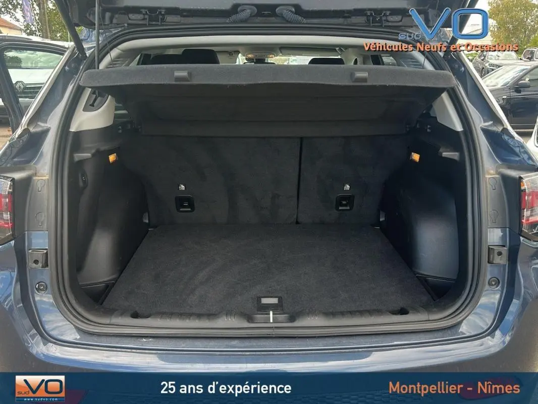 Coffre ouvert vu de l'arrière d'un Jeep Compass bleu 2023, montrant l'espace de chargement vide et la plage arrière relevée.