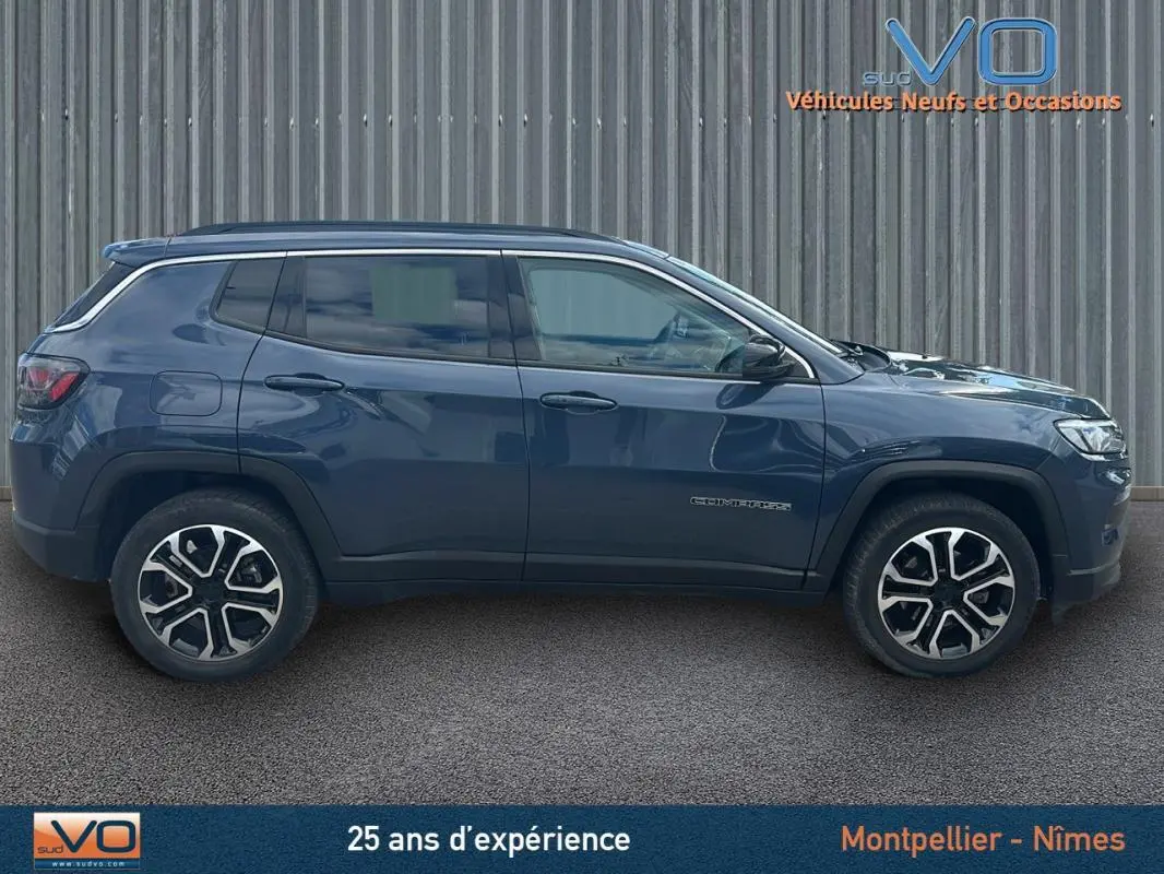 Vue de profil côté gauche d'un Jeep Compass bleu 2023 avec jantes 18 pouces et barres de toit visibles.