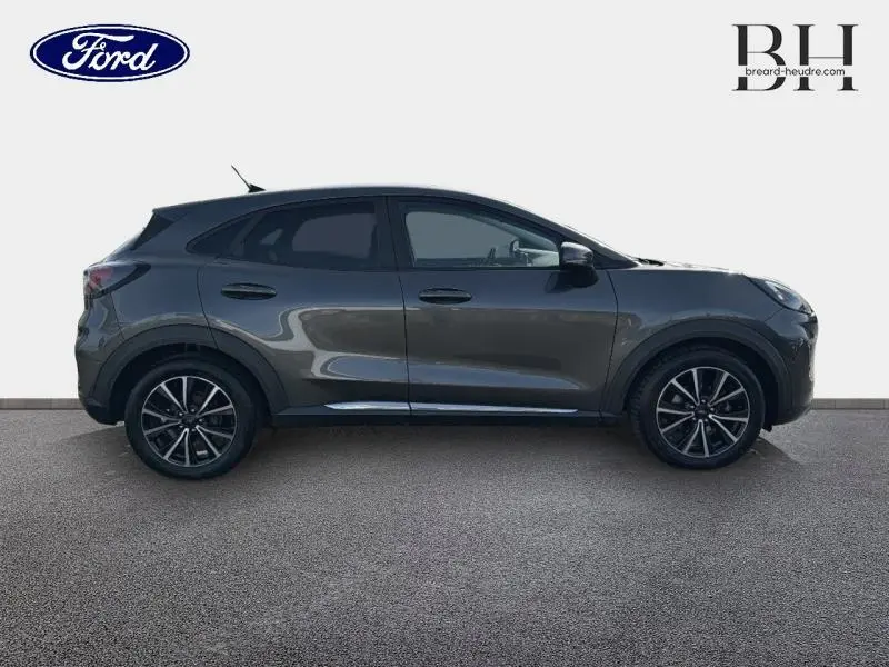Vue de profil droit du Ford Puma 1.0 EcoBoost 125ch Titanium gris métallisé avec jantes alliage noires.