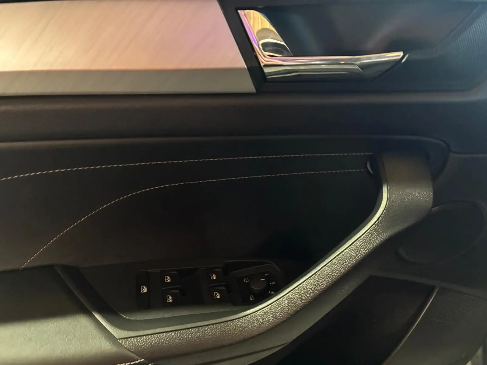 Détail de la porte intérieure côté conducteur du Skoda Kodiaq gris, avec commandes électriques et insert chromé.
