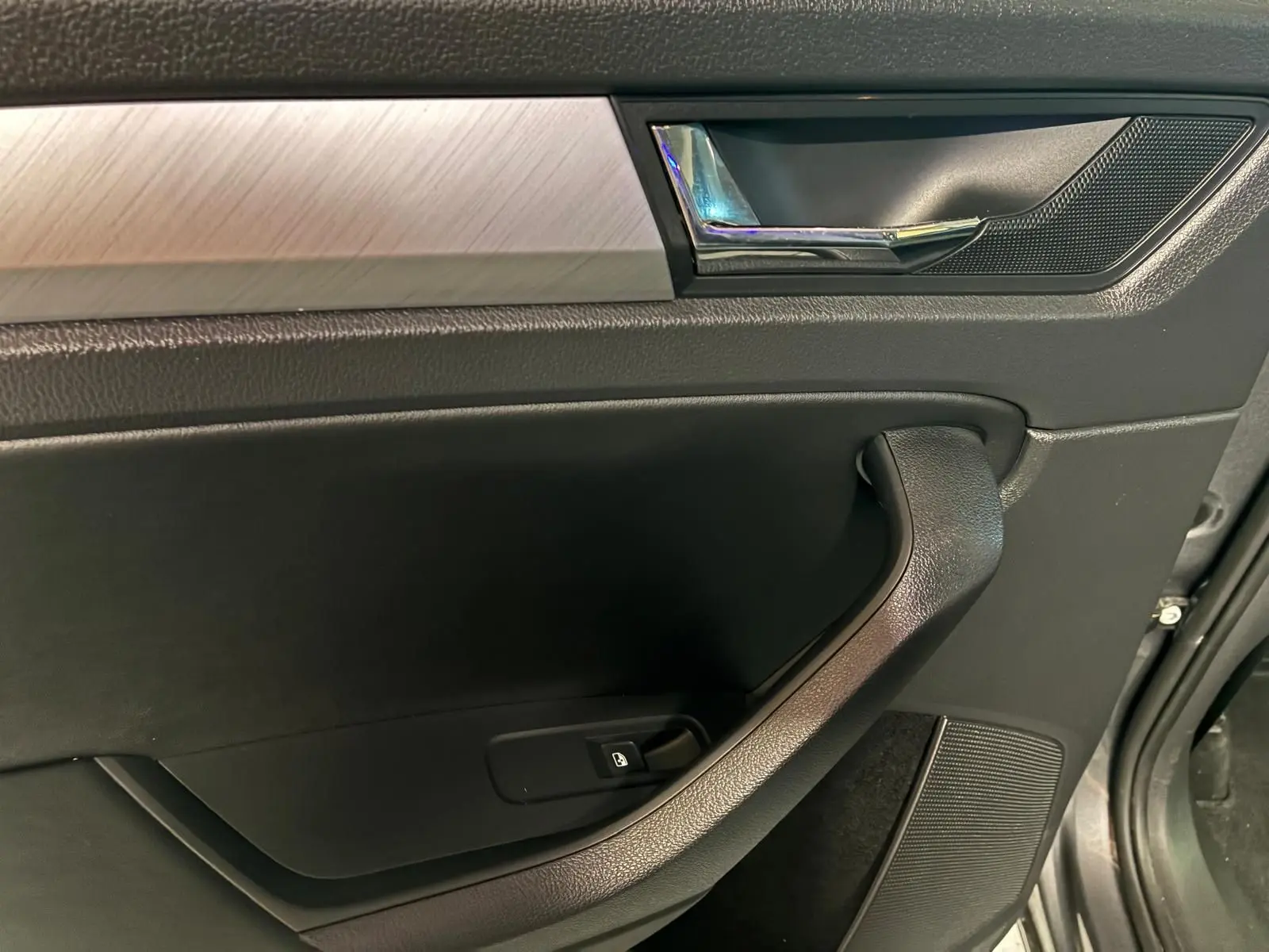 Gros plan sur la porte intérieure côté gauche du Skoda Kodiaq 2023, avec insert aluminium brossé et poignée chromée.