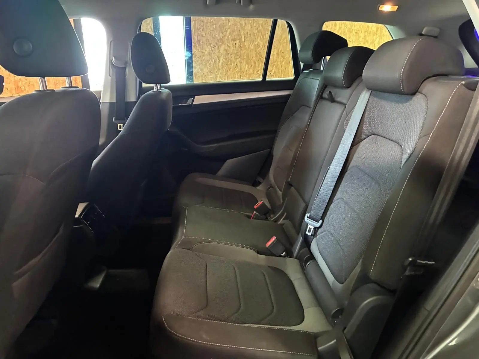Vue latérale intérieure des sièges arrière gris foncé du Skoda Kodiaq 7 places avec ceintures et appuie-têtes visibles.
