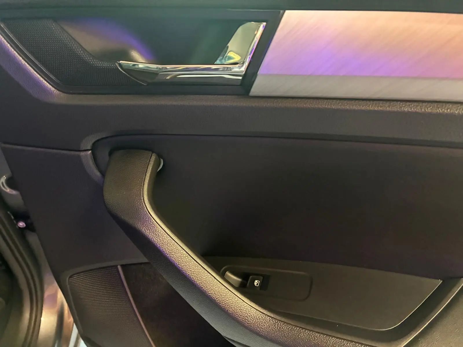 Gros plan sur la poignée intérieure côté gauche de la porte d’un Skoda Kodiaq gris avec insert décoratif aluminium.