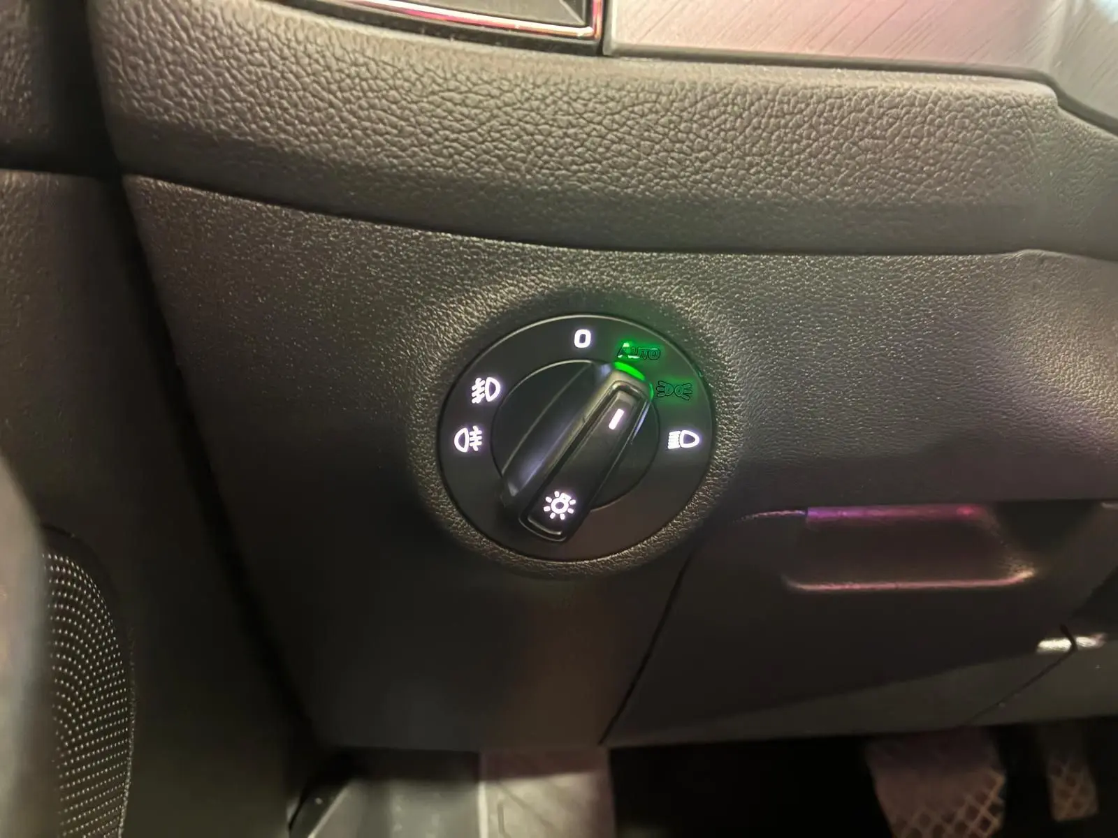 Gros plan sur le bouton de commande des phares du Skoda Kodiaq gris, avec indicateurs lumineux verts activés.