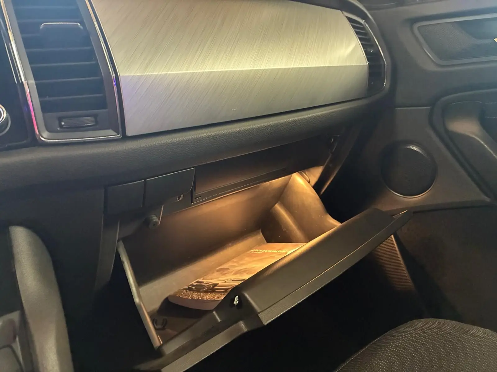 Intérieur du Skoda Kodiaq 2023, vue sur la boîte à gants ouverte avec éclairage intérieur et tableau de bord gris.