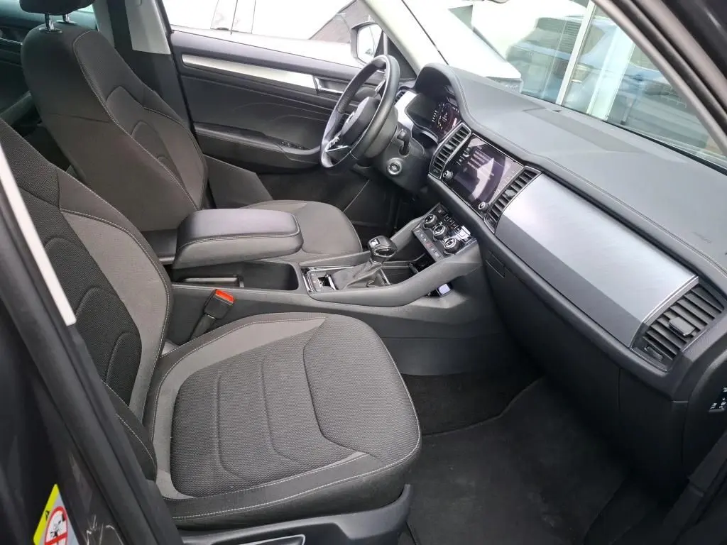 Vue intérieure côté conducteur du Skoda Kodiaq gris 2023, montrant sièges tissu, tableau de bord moderne et console centrale.