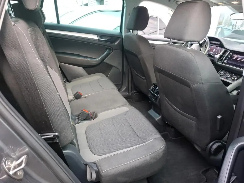 Vue intérieure côté gauche du Skoda Kodiaq 2023, sièges tissu gris et tableau de bord visible à l'avant.