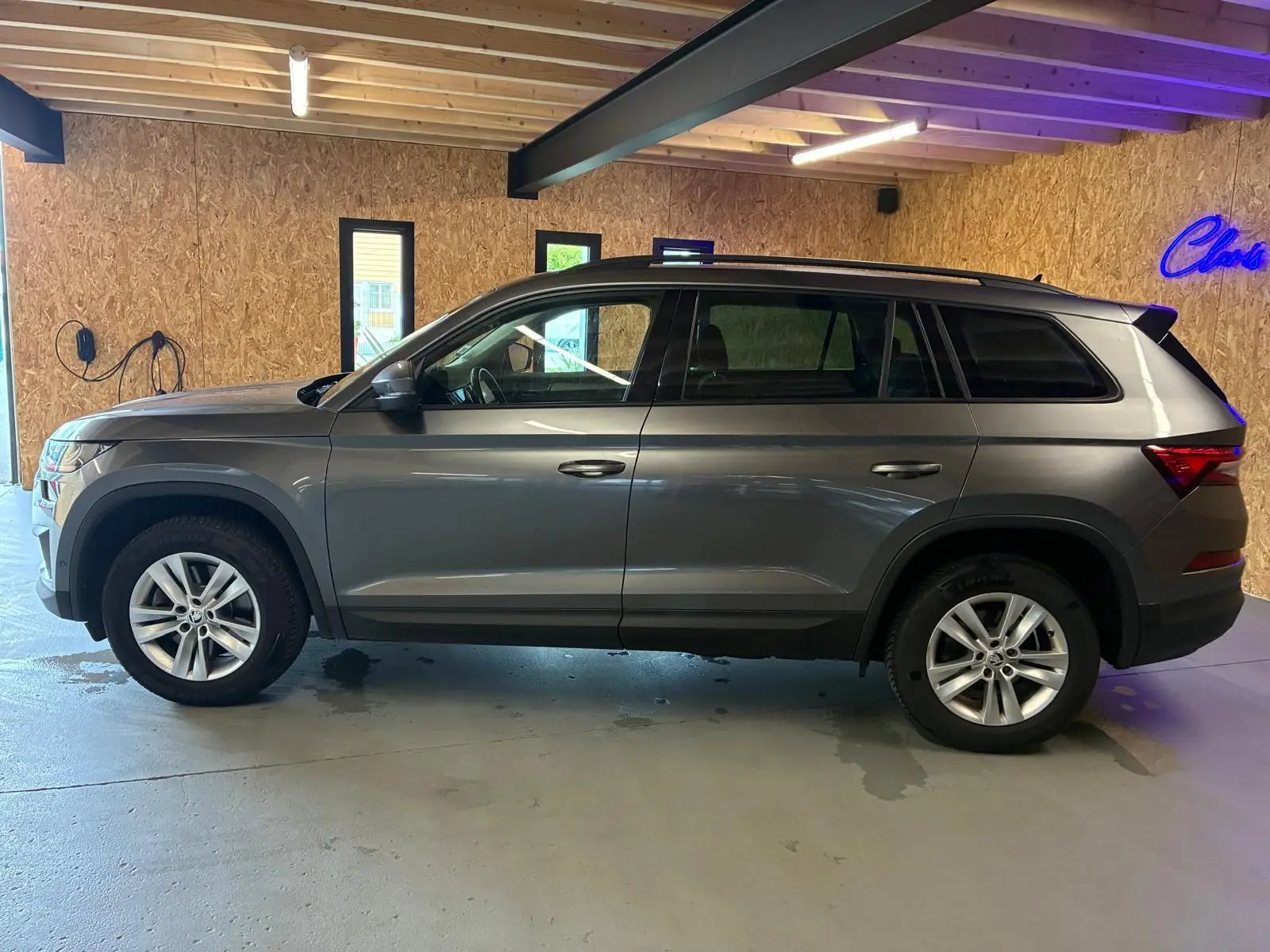 Vue de profil côté gauche d'un Skoda Kodiaq gris 2023 avec jantes alu 17 pouces dans un garage.