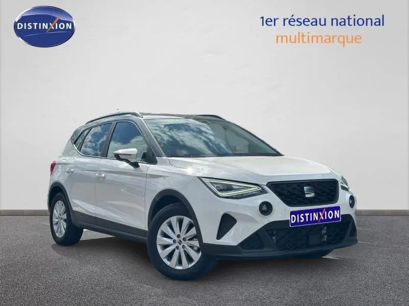 SEAT Arona blanc Candy avec toit gris Magnétique, vue 3/4 avant droit, jantes alu et calandre noire distinctive.