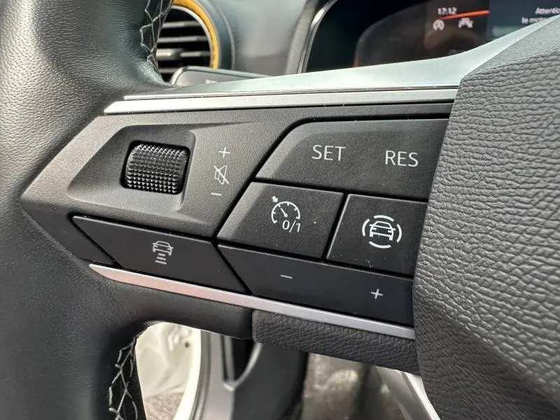Gros plan sur les commandes du volant cuir multifonction côté gauche d'une SEAT Arona 2025, boutons de régulateur de vitesse.