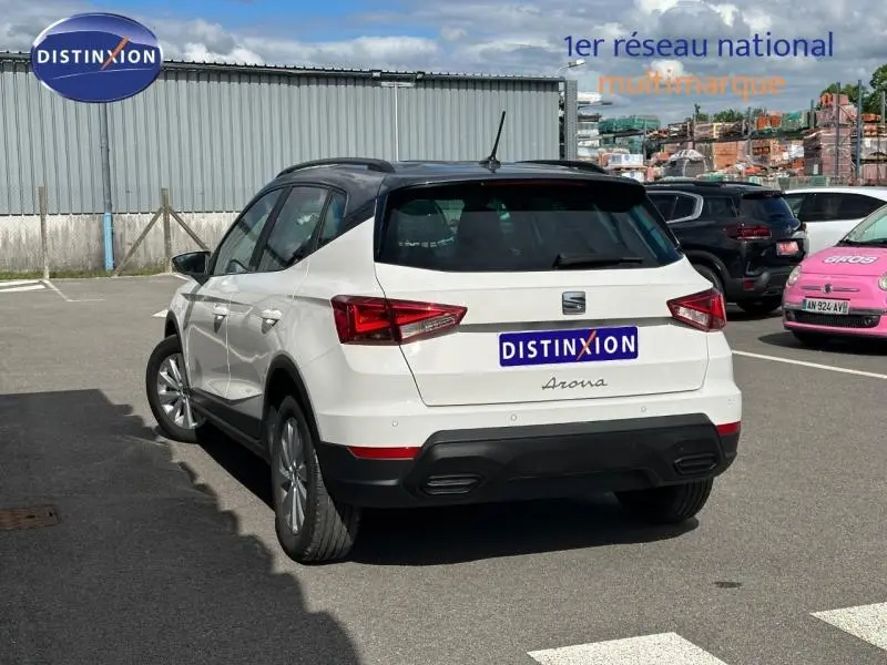 Vue 3/4 arrière droite d'une SEAT Arona blanc Candy avec toit gris magnétique, jantes alu et feux LED distinctifs.