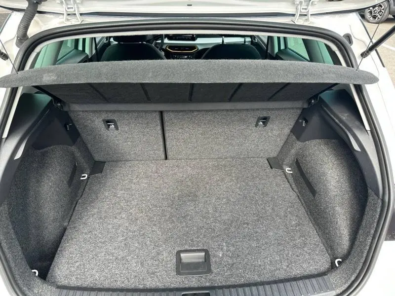 Coffre ouvert vu de l'arrière d'un SEAT Arona blanc Candy avec intérieur gris et tablette cache-bagages relevée.