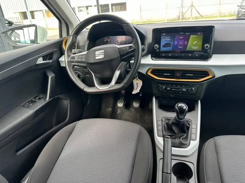 Vue intérieure avant du SEAT Arona 2025, volant cuir multifonction, écran tactile et levier de vitesse manuel.
