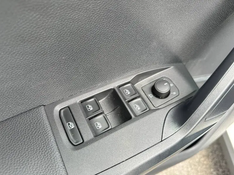 Gros plan sur les commandes de lève-vitres et réglage des rétroviseurs côté conducteur d'une SEAT Arona blanc Candy.