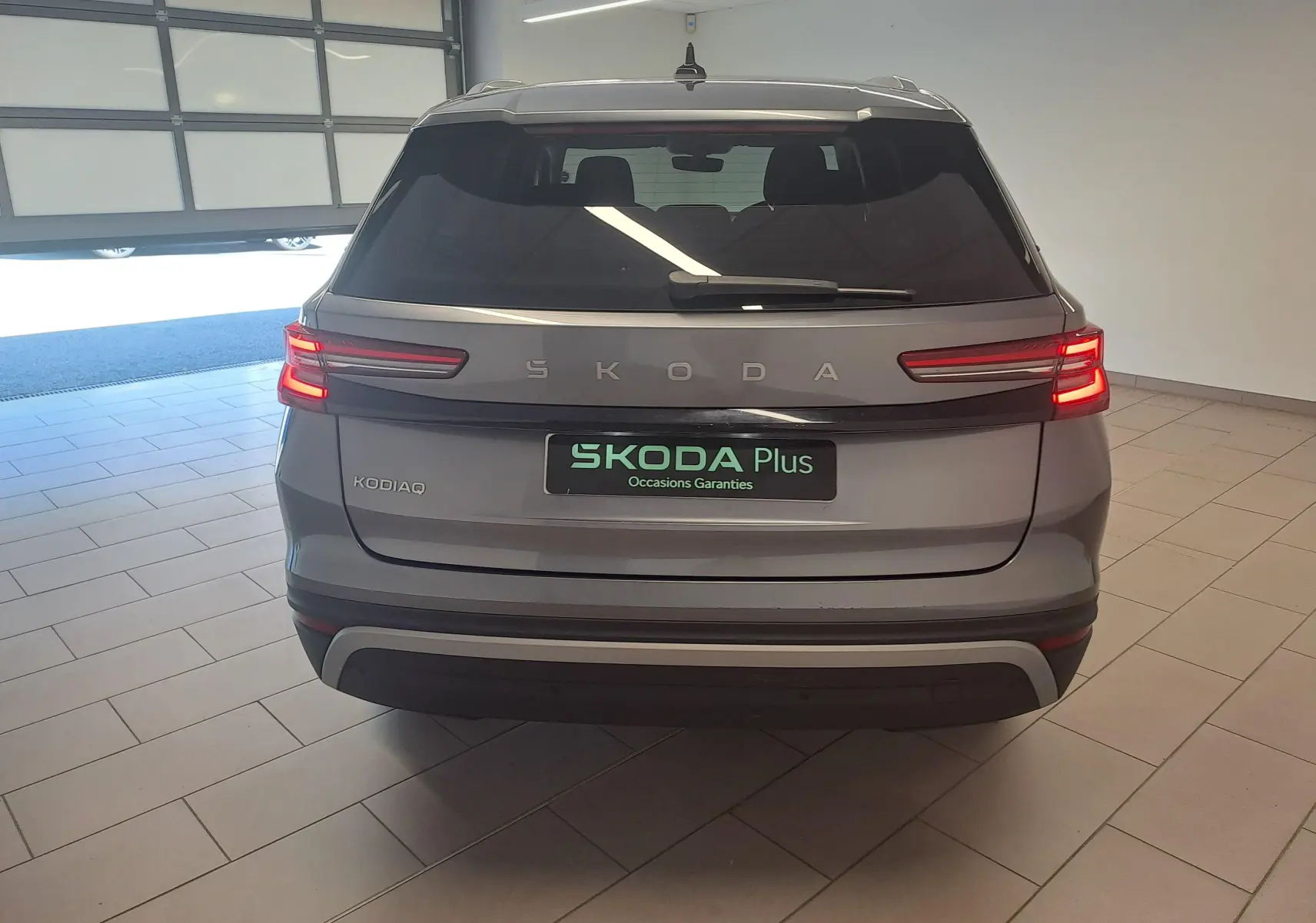 Vue arrière d'un Skoda Kodiaq gris graphite 2025 avec feux LED allumés, dans un garage éclairé.