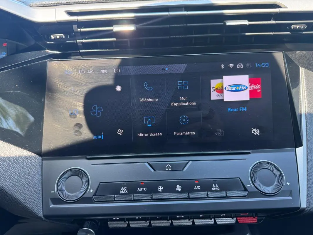 Vue rapprochée de l'écran tactile central et des commandes de climatisation du Peugeot 308 gris 2025.