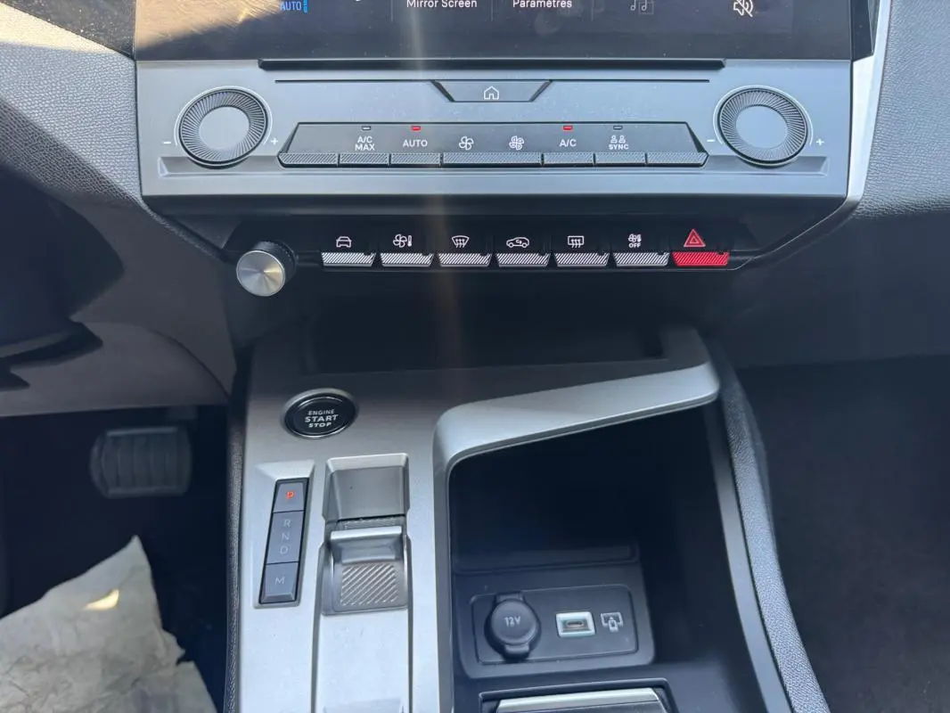 Vue rapprochée du tableau de bord et console centrale grise de la Peugeot 308 2025 avec commandes climatisation et levier de boîte auto.