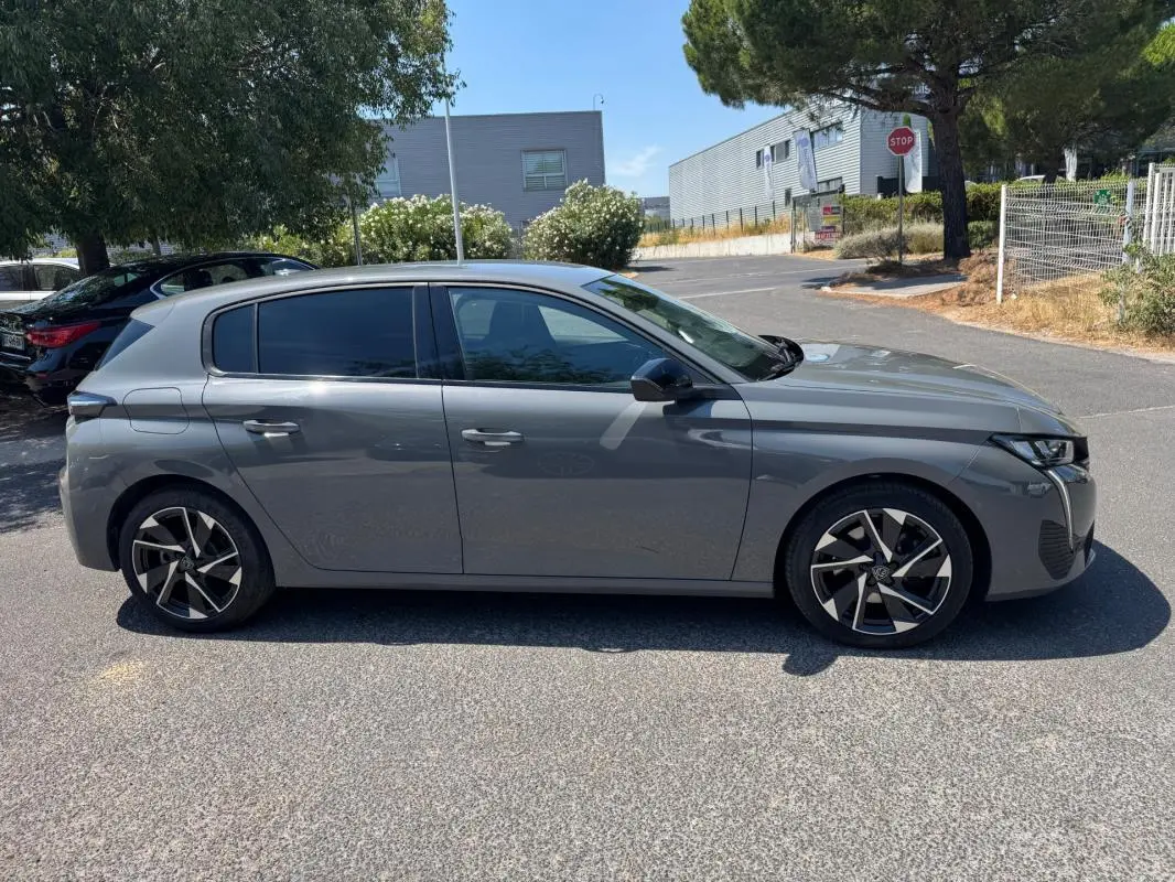 Peugeot 308 gris vue de profil côté gauche, avec jantes alliage 17 pouces et vitres teintées.
