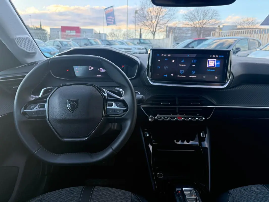 Vue intérieure frontale du tableau de bord et volant noir de la Peugeot 208 Hybrid 110 e-DCS6 Allure 2024 avec écran tactile.