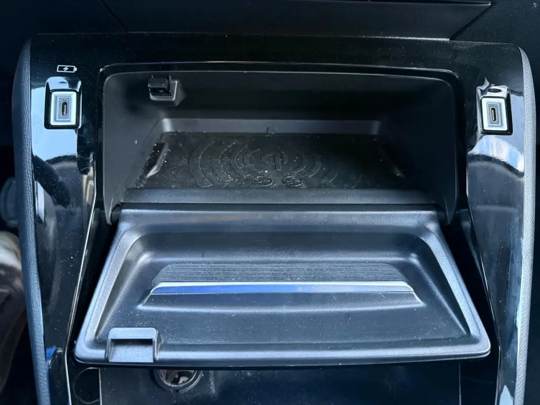Vue rapprochée de la console centrale noire du Peugeot 208 Hybrid 110 e-DCS6 Allure avec ports USB et espace de rangement.