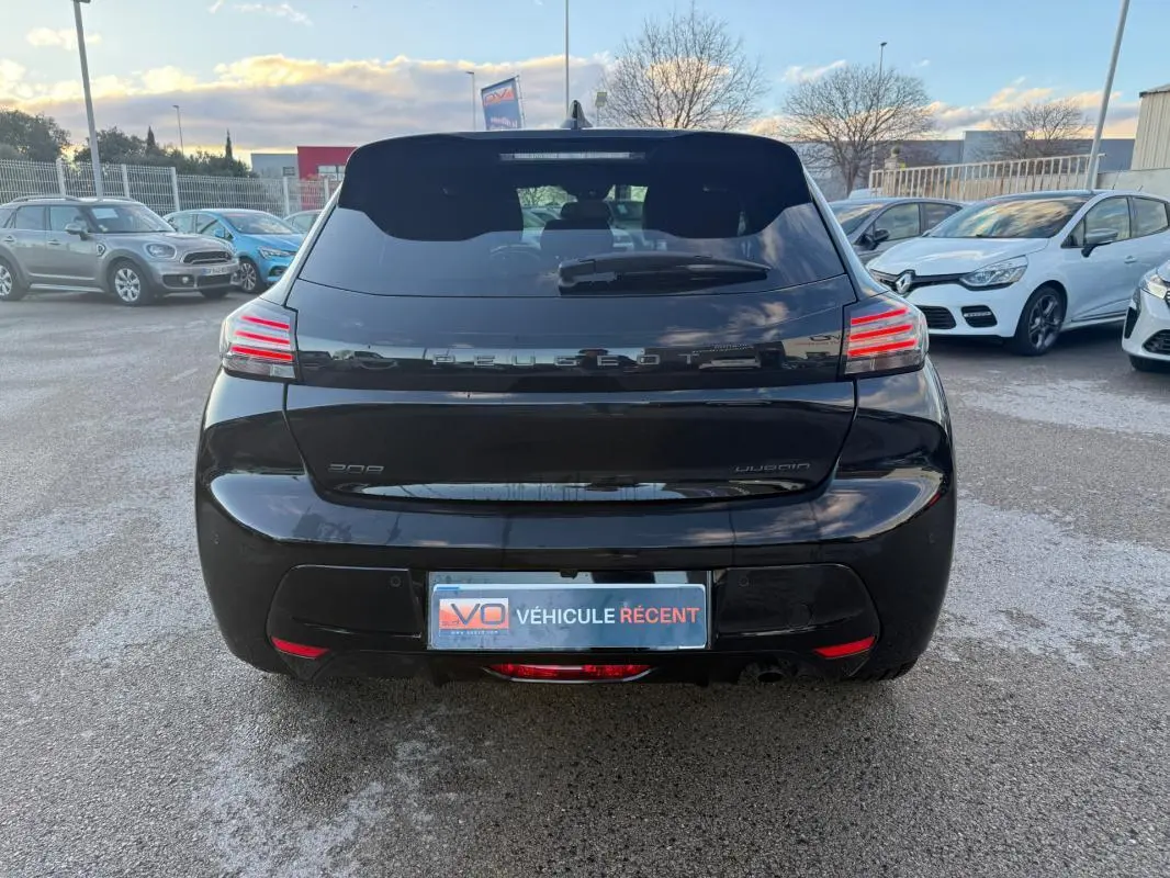 Vue arrière d'une Peugeot 208 Hybrid 110 noire, avec feux LED distinctifs et jantes alliage visibles.