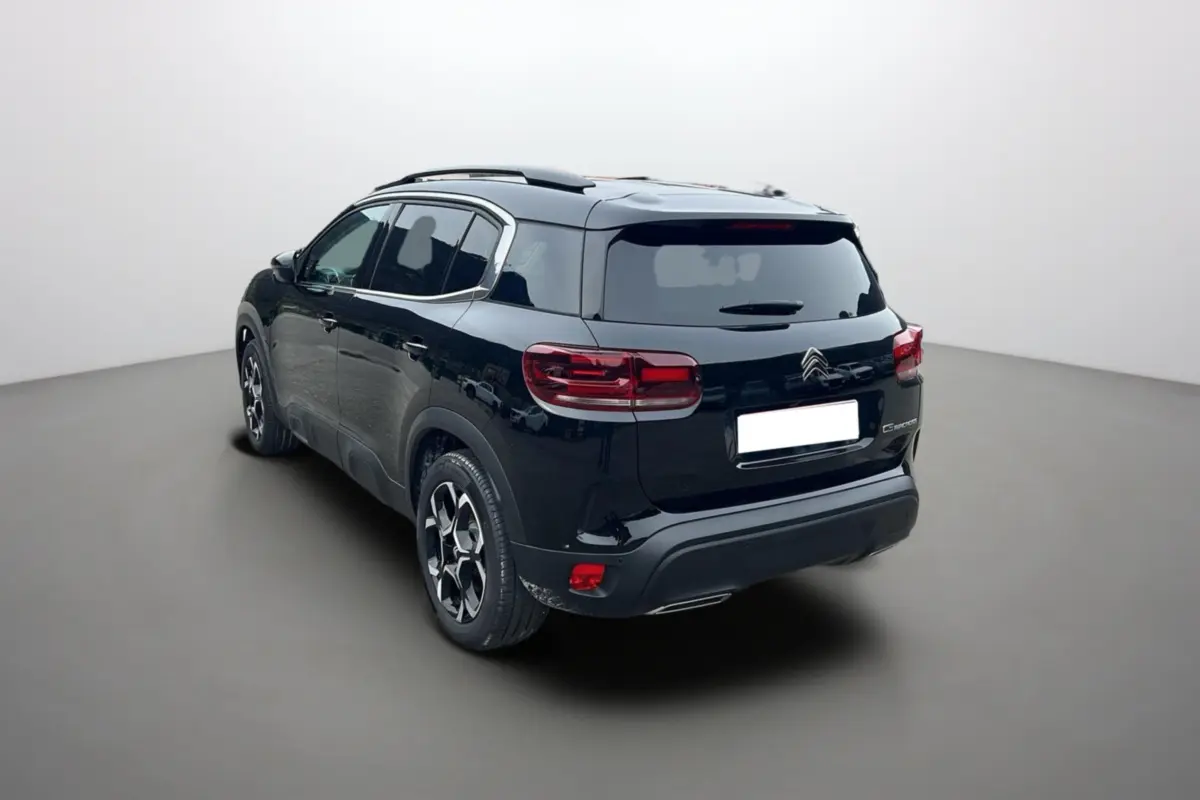 Vue 3/4 arrière droite d'un Citroën C5 Aircross Hybrid noir avec barres de toit et vitres surteintées.
