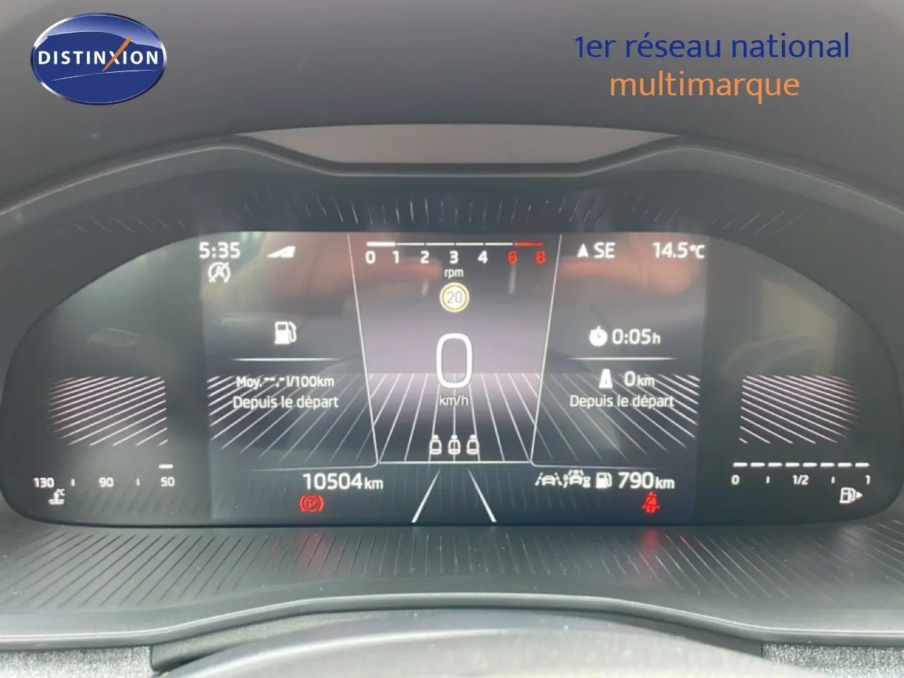 Vue rapprochée du tableau de bord numérique du Skoda Scala blanc glacier, affichant la vitesse à 0 km/h et 10 504 km au compteur.