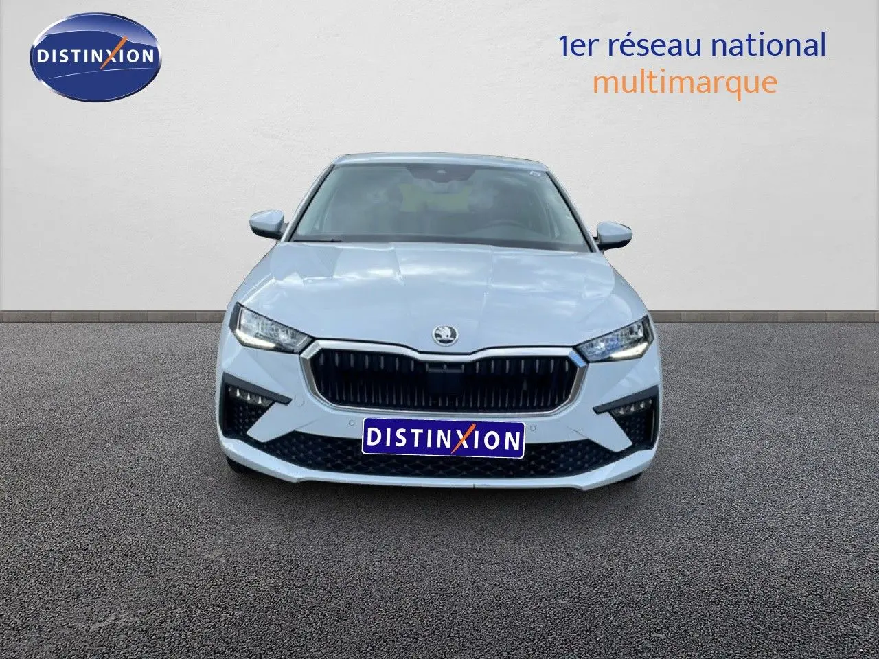 Vue frontale d'une Skoda Scala blanc glacier avec calandre noire et phares LED allumés sur fond neutre.