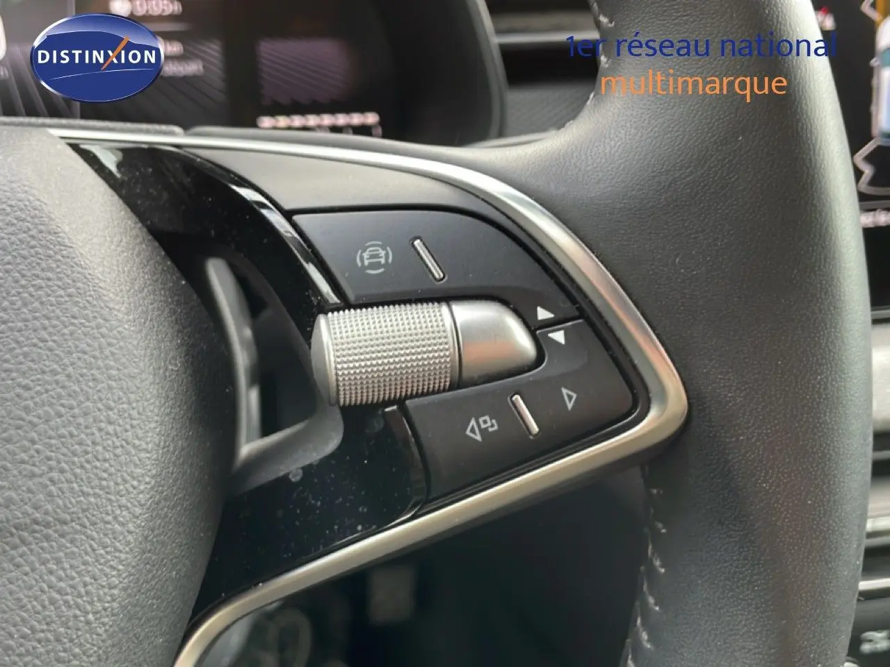 Gros plan sur les commandes du volant en cuir noir de la Skoda Scala 2025, avec molette et boutons multifonctions.
