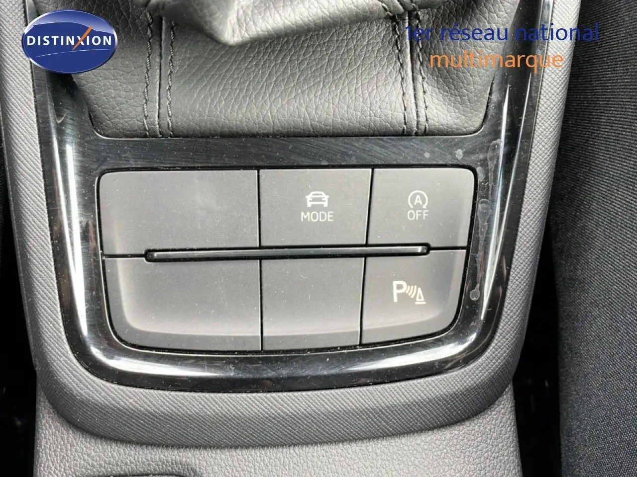 Gros plan sur les boutons de commande du mode de conduite et assistance au stationnement d’un Skoda Scala blanc glacier.