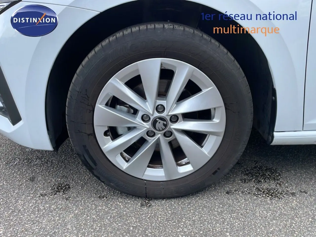 Gros plan sur la roue avant gauche d'une Skoda Scala blanc glacier avec jante alliage à dix branches.