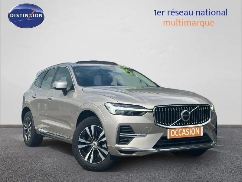 Volvo XC60 gris vue 3/4 avant avec calandre chromée et jantes alliage distinctives, sur fond neutre.