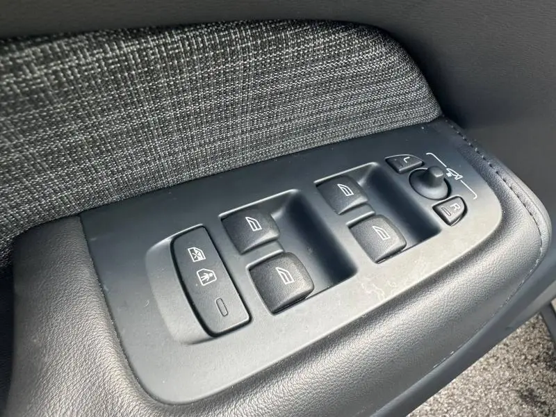 Commande des vitres et rétroviseurs côté conducteur du Volvo XC60 gris, avec habillage tissu et cuir noir.
