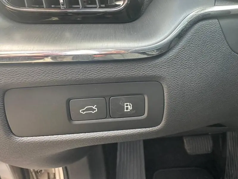 Boutons d'ouverture du coffre et de la trappe à carburant sur la console côté conducteur d'un Volvo XC60 gris 2024.